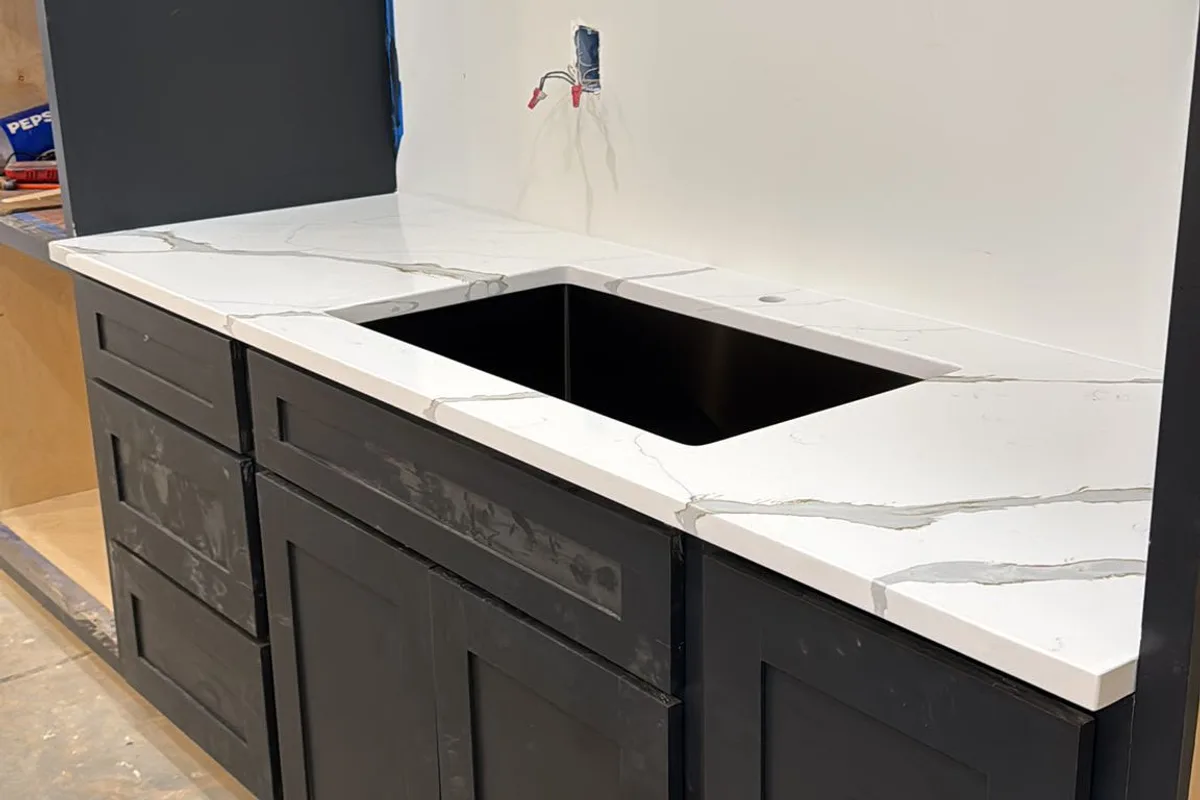 Black shaker cabinets with a quartz countertop and undermount sink being installed