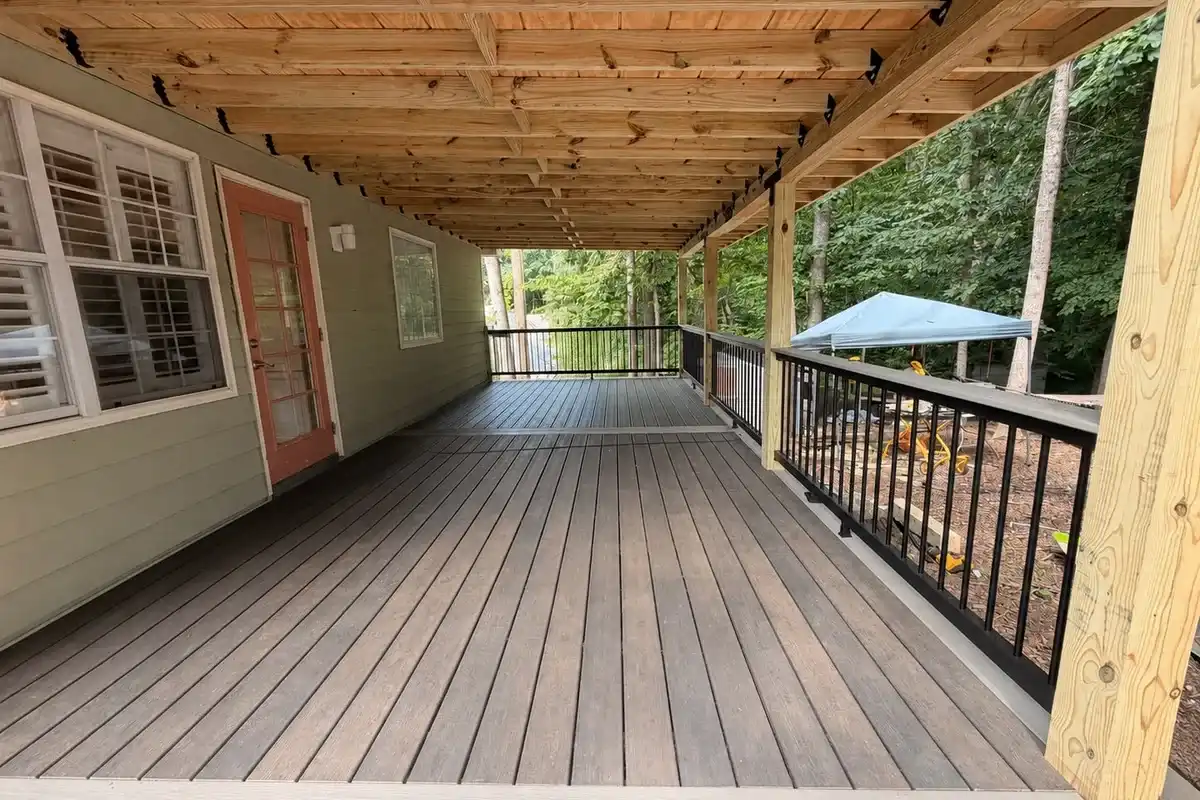 Covered composite deck with black railings along the back of a home