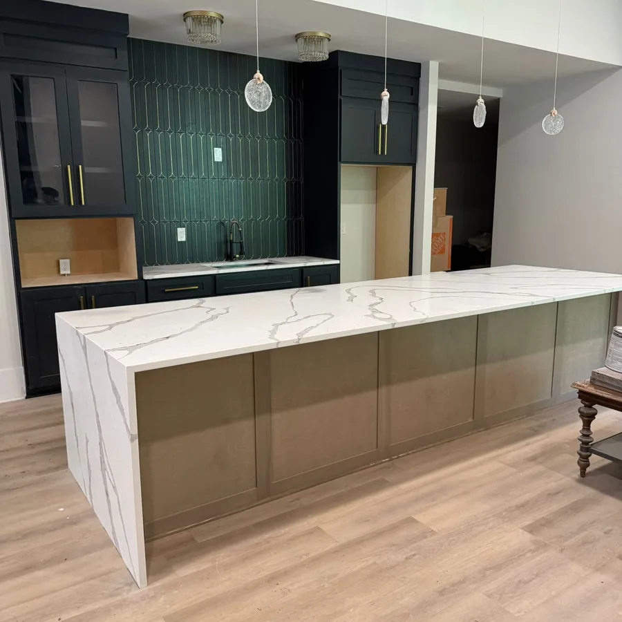 Remodeled kitchen island with a waterfall quartz countertop and glass pendant lights