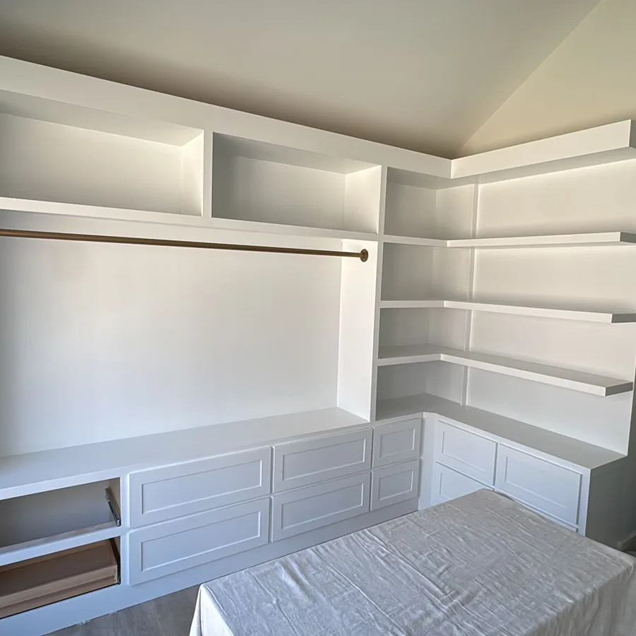 Custom white built-in shelves, drawers and closet rod in a bedroom