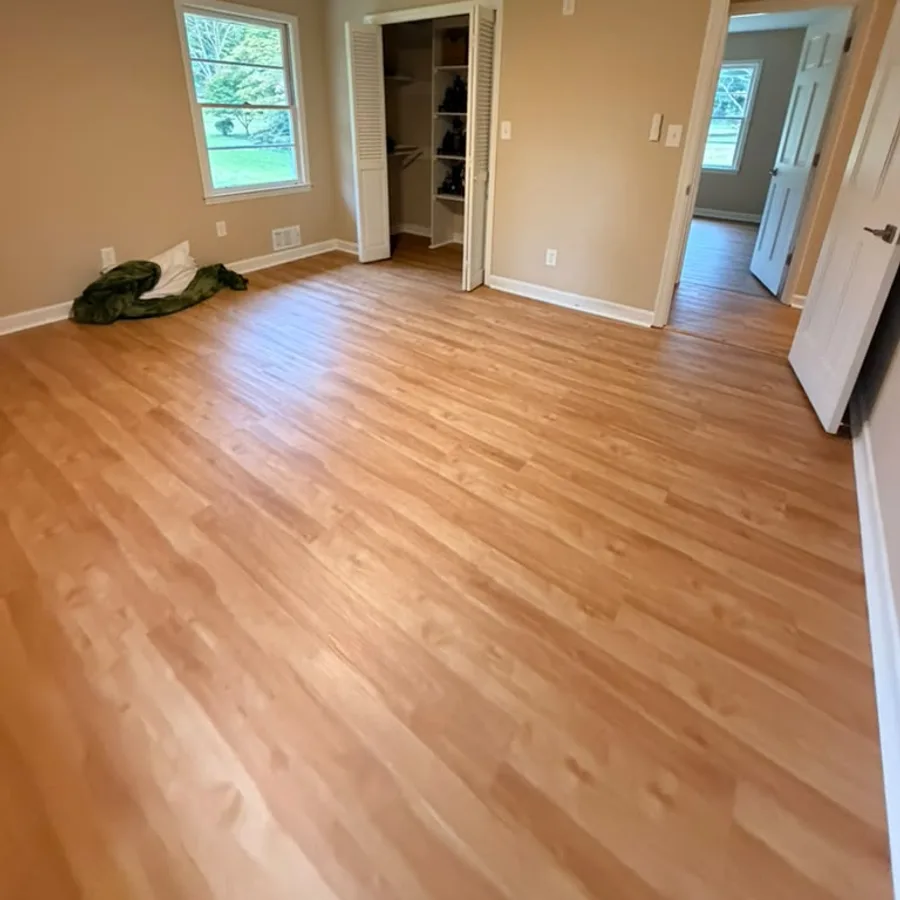 Bedroom with new wood-look vinyl plank flooring and white baseboards