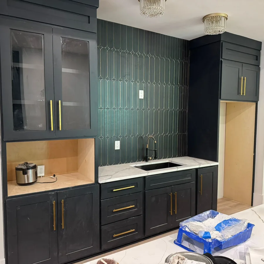 Black shaker cabinets with brass pulls, a quartz countertop and a green arched tile backsplash